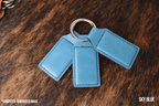 Three Sky Blue Premium Leatherette keychains fanned out on a split ring, showing the blank engraving panel.