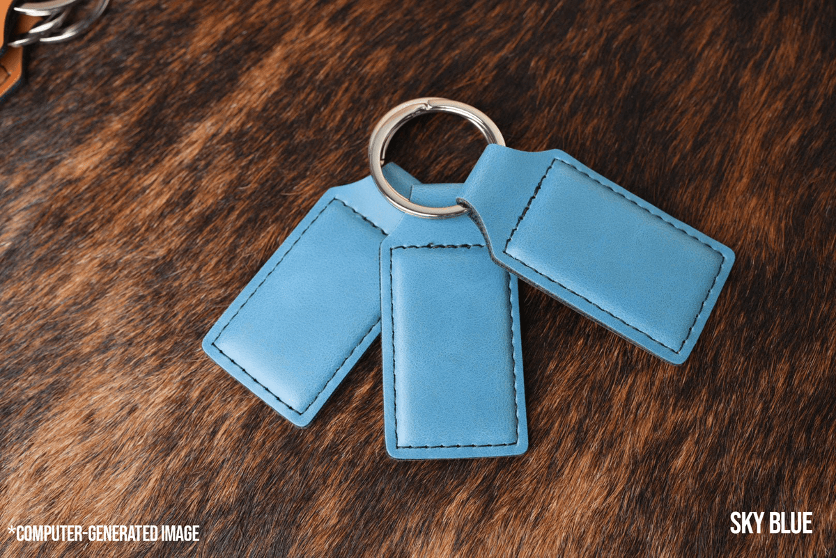 Three Sky Blue Premium Leatherette keychains fanned out on a split ring, showing the blank engraving panel.