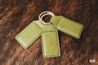 Three Olive green Premium Leatherette keychains fanned out on a split ring, showing the blank engraving panel.