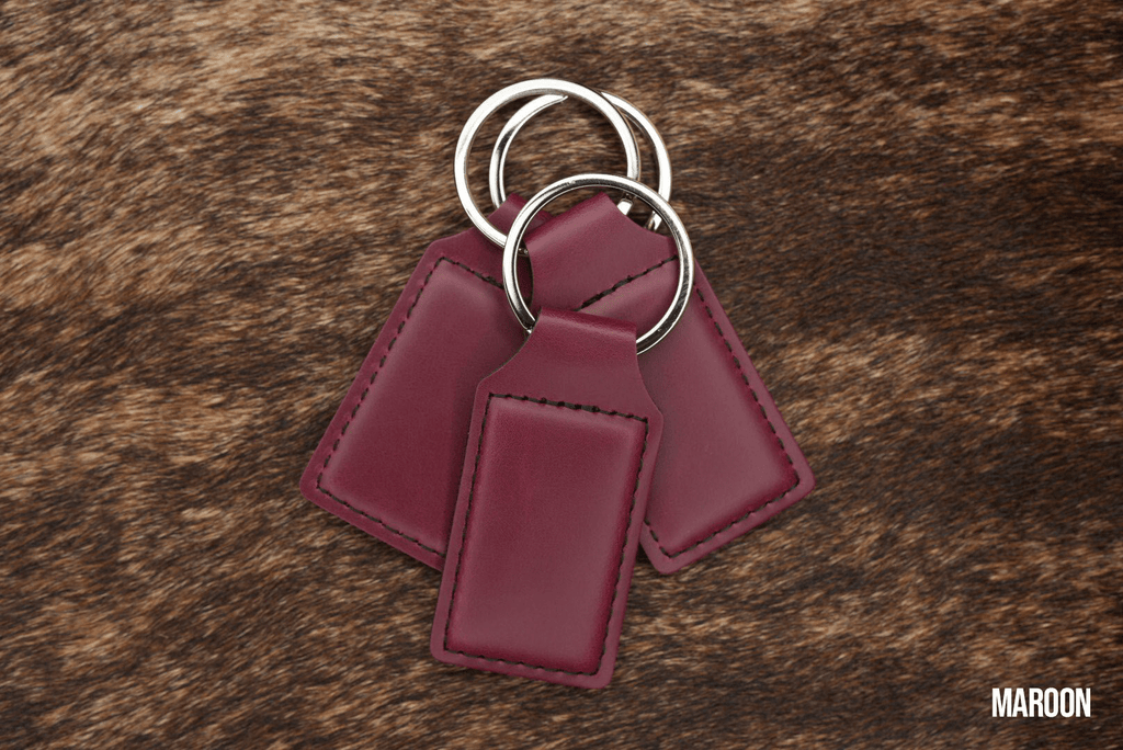 Three Maroon deep red Premium Leatherette keychains fanned out on a split ring, showing the blank engraving panel.