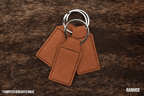 Three Rawhide tan Premium Leatherette keychains fanned out on a split ring, showing the blank engraving panel.