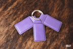 Three Violet lavender Premium Leatherette keychains fanned out on a split ring, showing the blank engraving panel.