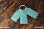 Three Sea Foam mint green Premium Leatherette keychains fanned out on a split ring, showing the blank engraving panel.