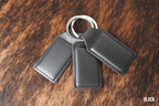 Three Black Premium Leatherette keychains fanned out on a split ring, showing the blank engraving panel.