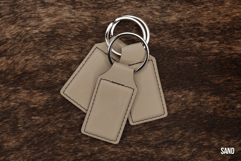 Three Sand beige Premium Leatherette keychains fanned out on a split ring, showing the blank engraving panel.