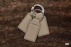 Three Sand beige Premium Leatherette keychains fanned out on a split ring, showing the blank engraving panel.