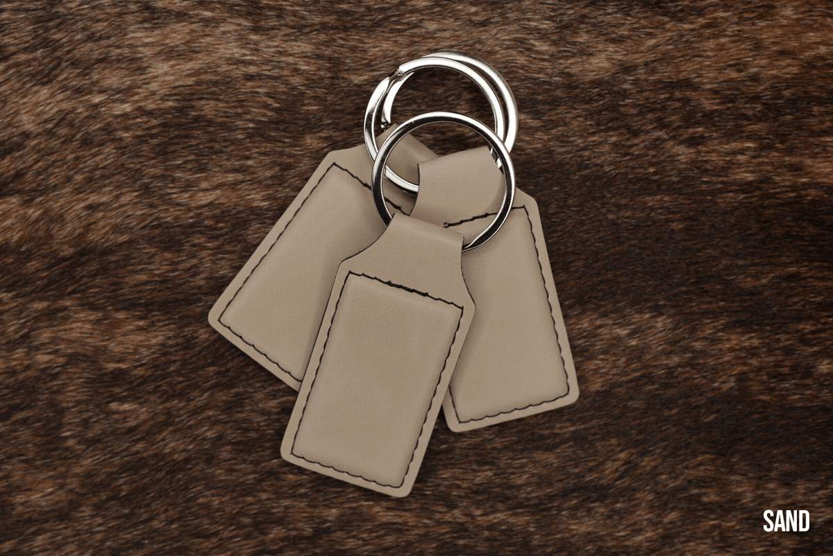 Three Sand beige Premium Leatherette keychains fanned out on a split ring, showing the blank engraving panel.