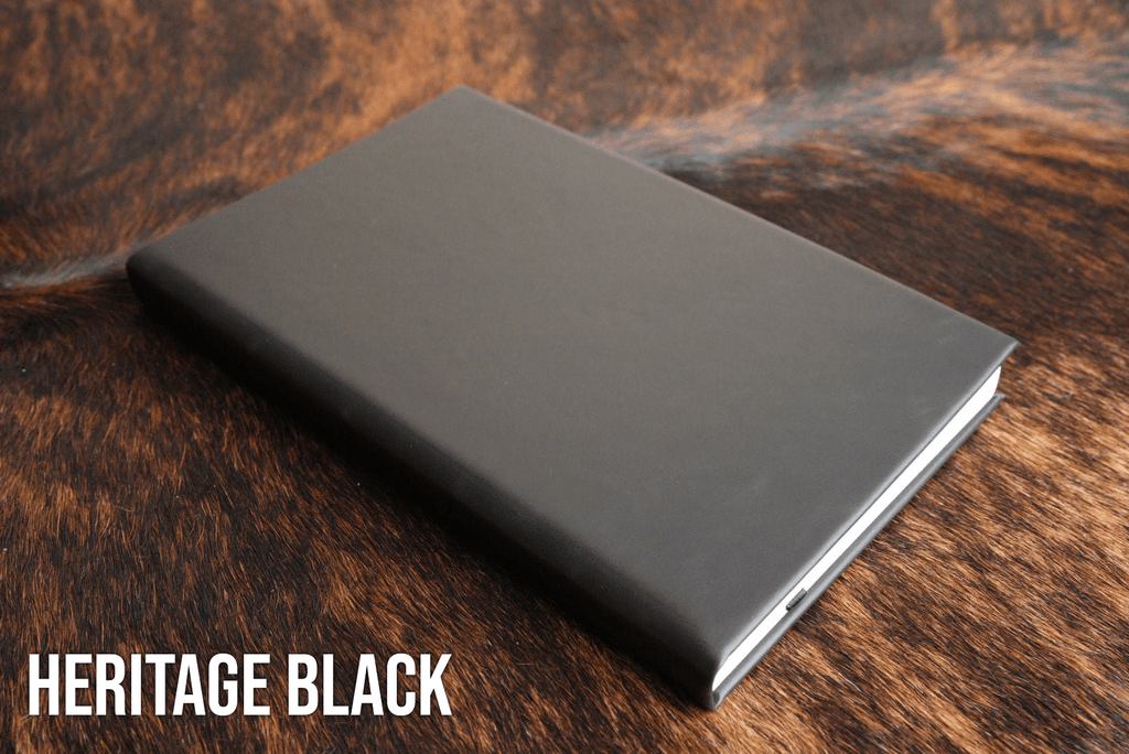 Heritage Black Premium Leatherette journal cover, shown closed on a cowhide surface