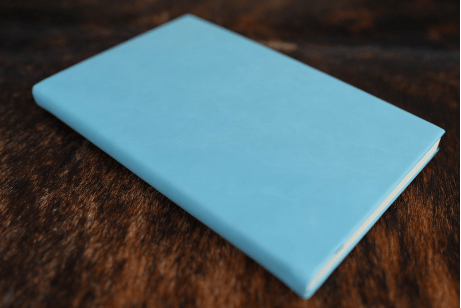 Sky Blue Premium Leatherette journal cover, shown closed on a cowhide surface