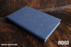Indigo blue Premium Leatherette journal cover, shown closed on a cowhide surface