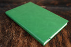 Kelly Green Premium Leatherette journal cover, shown closed on a cowhide surface