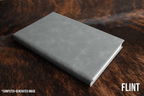 Flint gray Premium Leatherette journal cover, shown closed on a cowhide surface