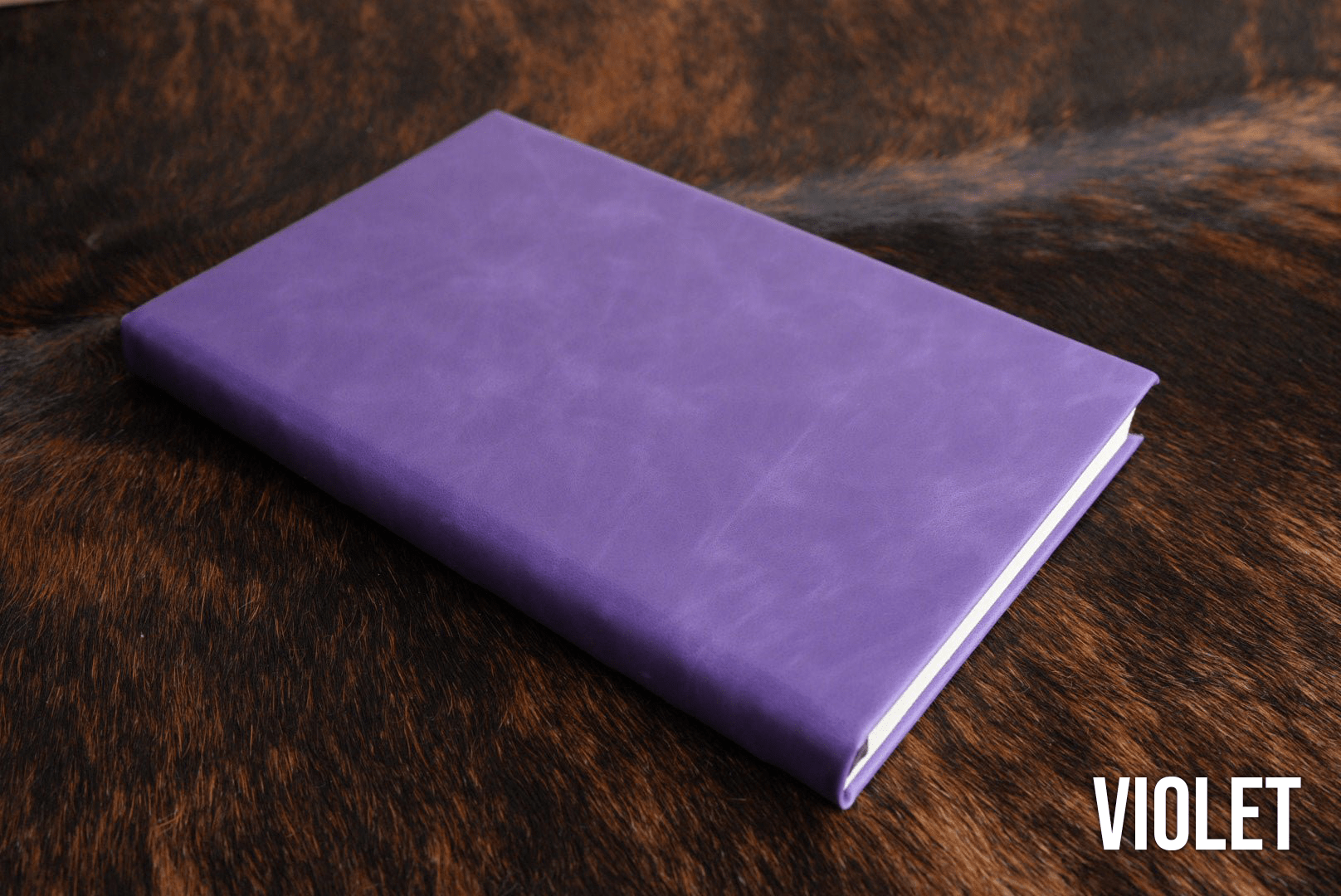 Violet Premium Leatherette journal cover, shown closed on a cowhide surface