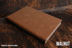 Walnut brown Premium Leatherette journal cover, shown closed on a cowhide surface