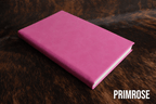 Primrose pink Premium Leatherette journal cover, shown closed on a cowhide surface