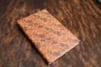 Drake Camo Premium Leatherette journal cover in orange, rust and tan, shown closed on a cowhide surface
