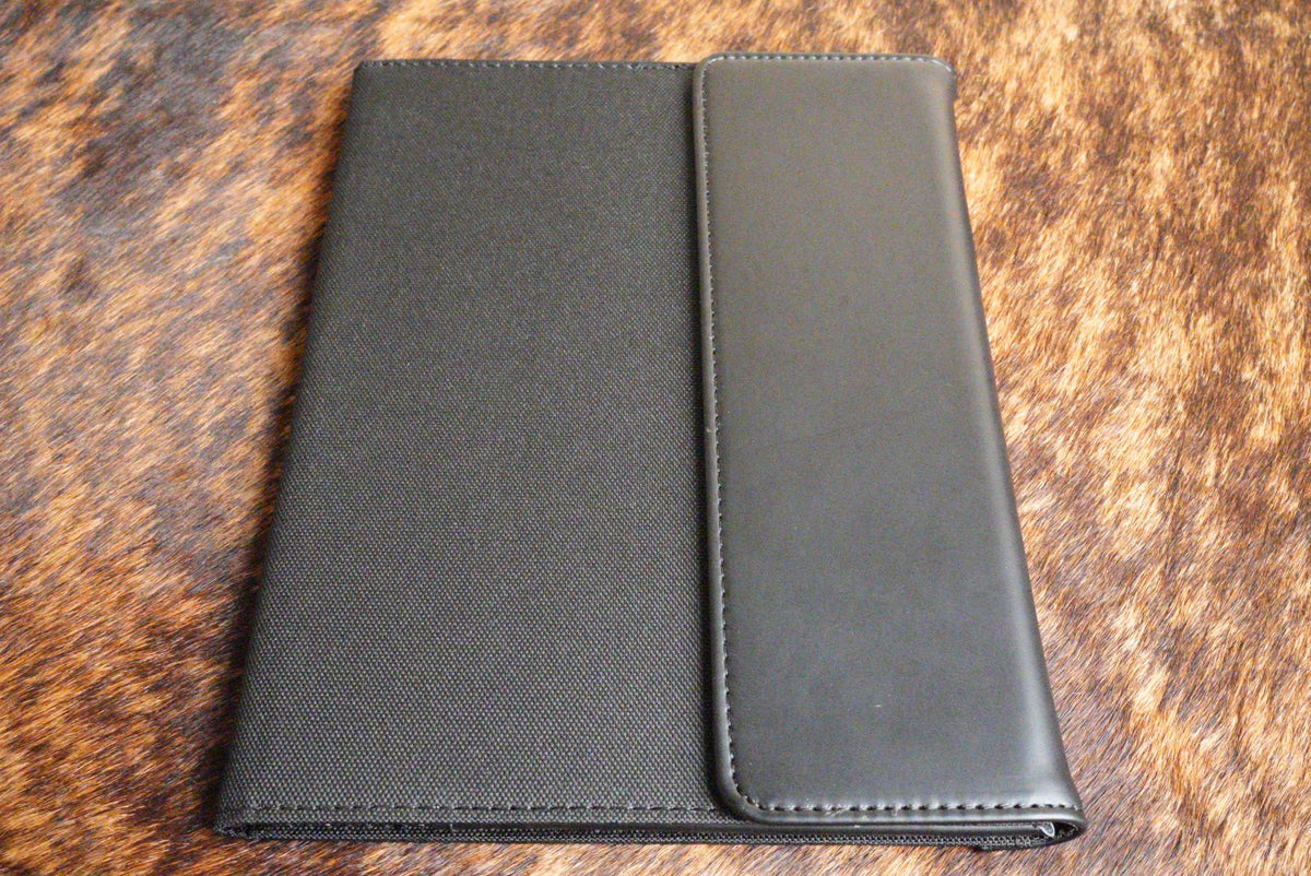 Black Premium Leatherette padfolio with a black interior that engraves to silver, shown closed on a cowhide surface