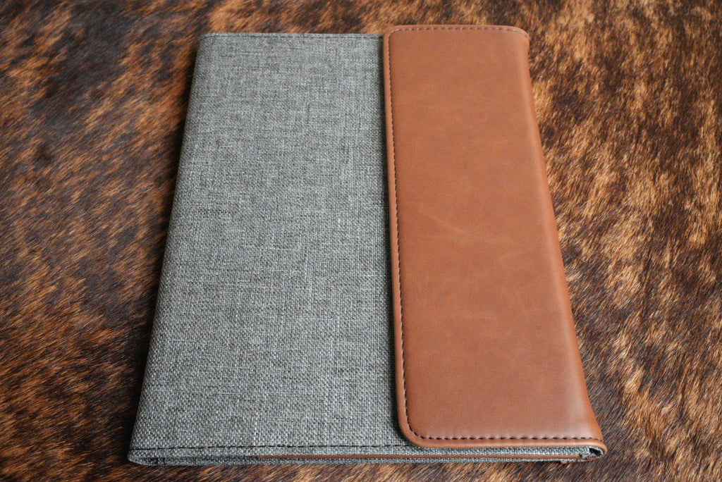 Walnut brown Premium Leatherette padfolio, shown closed on a cowhide surface