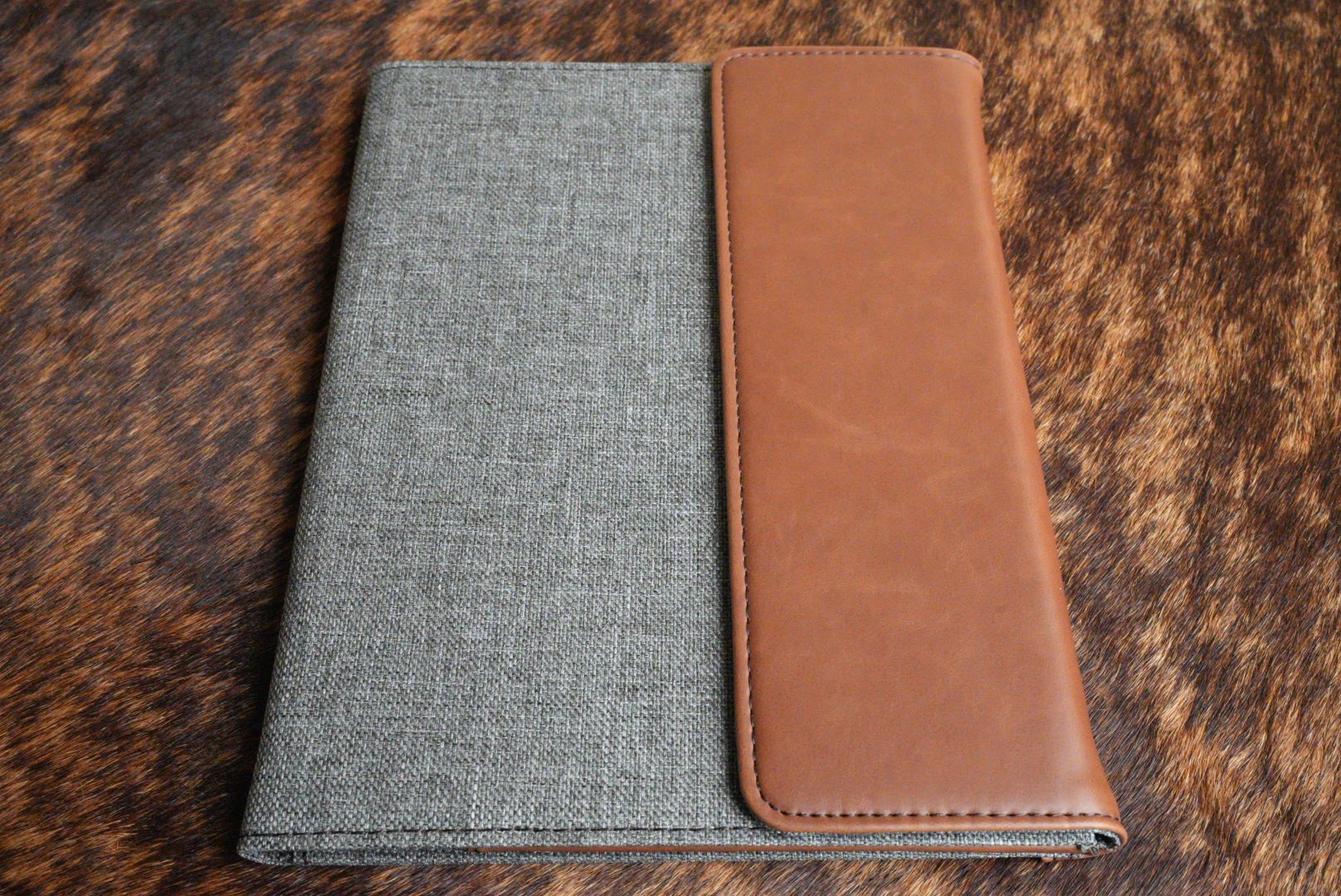 Walnut brown Premium Leatherette padfolio, shown closed on a cowhide surface