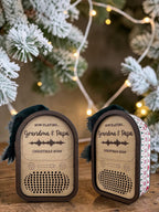 Two Round Top Radio ornaments engraved Now Playing Grandma and Papa with a sound wave, one wrapped in Ugly Christmas Sweater leatherette