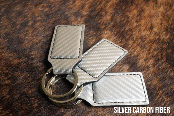 Three silver carbon fiber Premium Leatherette keychains with a woven texture, fanned out on a split ring.