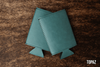 Topaz teal Premium Leatherette slim can coolers, sized for slim cans, laid flat and collapsed.