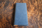 Indigo blue Premium Leatherette tally book, shown closed on a cowhide surface