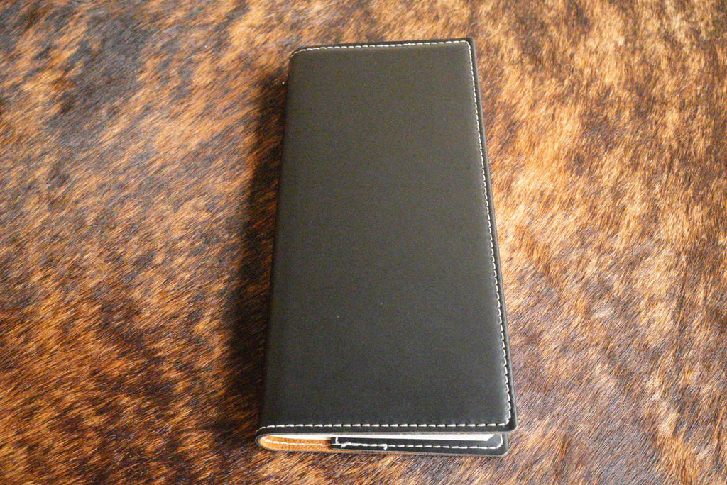 Black Premium Leatherette tally book that engraves to silver, shown closed on a cowhide surface