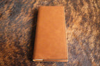 Heritage Rawhide Premium Leatherette tally book, shown closed on a cowhide surface