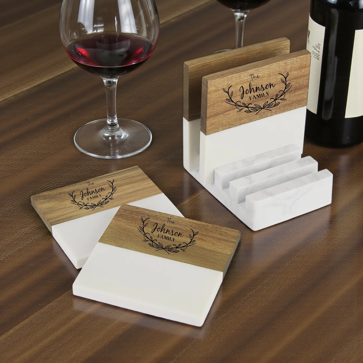 Wood and marble coasters engraved with "The Johnson Family" beside a glass of red wine