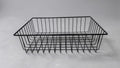 Black wire gift basket, a rectangular open-top frame of welded wire with flared corner legs, on a light grey surface.